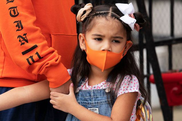 Kindergarten student Katalina Vidal wearing an orange mask holds her father's hand as she waits to enter PS 179 elementary school in Kensington.